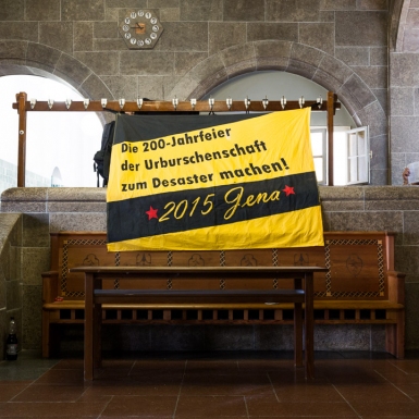 Demonstranten verstecken sich hinter Zetteln im Eingangsbereich des Universitäshauptgebäudes. Direkt nebenan fand der Festakt zur 200. Jahrfeier der jenaischen Burschenschaft statt.